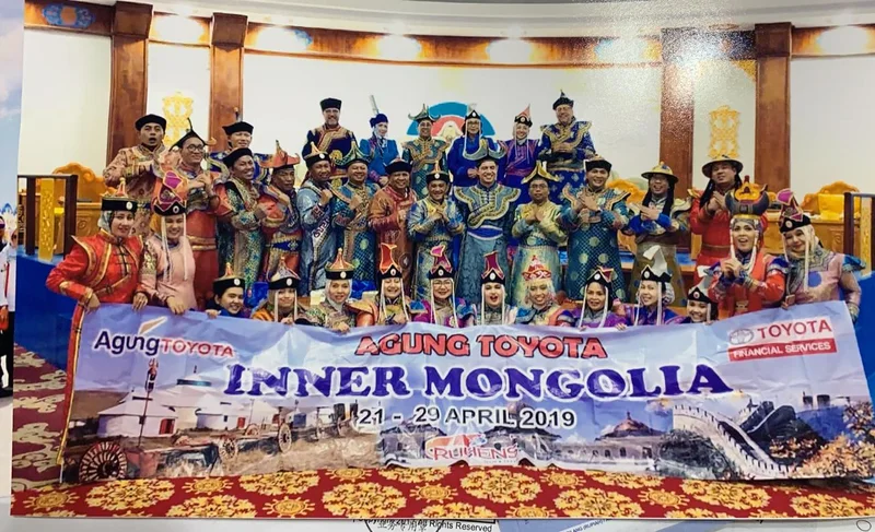 Grup perjalanan Ruhens mengenakan pakaian tradisional dengan spanduk Agung Toyota di Mongolia.