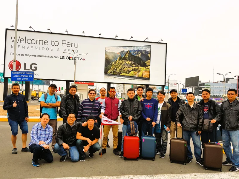 Peserta perjalanan Ruhens berfoto bersama koper di depan papan selamat datang di Peru.